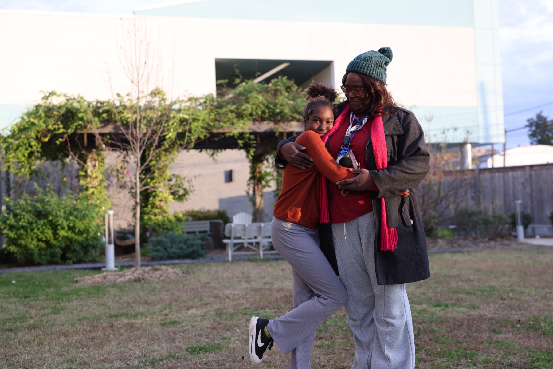 An adult and child embracing in an outdoor courtyard